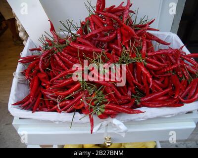 fresh red peppers in a basket on display in a shop Stock Photo