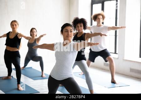 Indian coach training group of people performing Warrior two position Stock Photo