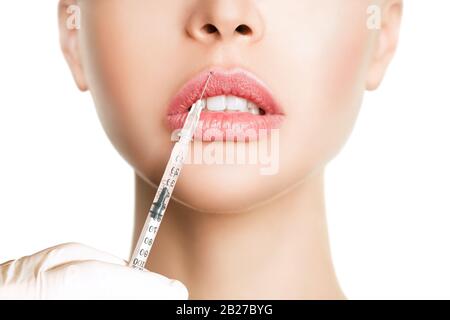 Close up of hands of cosmetologist making botox injection in female lips. She is holding syringe. The young beautiful woman lip correction procedure Stock Photo