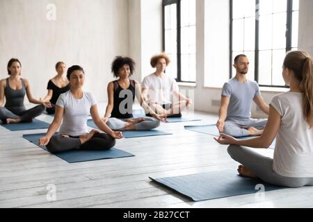 Indian ethnicity woman with like-minded people meditating indoors Stock Photo