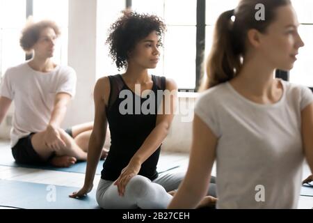 African woman with associates practicing yoga seated in lotus pose Stock Photo