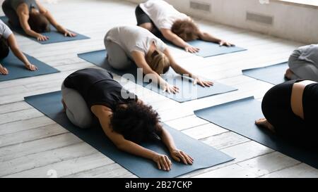Group of people lying on mats performing Child Pose asana Stock Photo