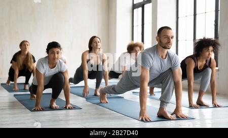 Diverse people performing Low lunge forward or Ashva Sanchalanasana indoors Stock Photo