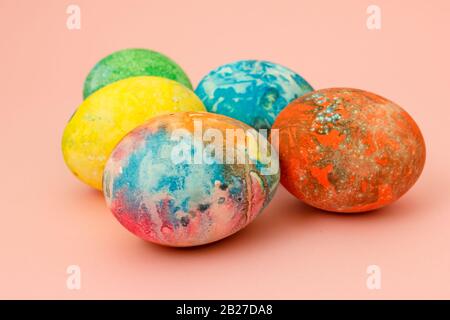 Four multi-colored Easter eggs on pink background top view, space for text. Concept happy easter day. Stock Photo