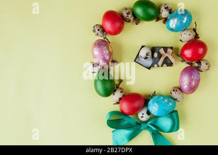 Gift and painted eggs Easter Frame in circle shape on a yellow background. Copy space, Top view Stock Photo