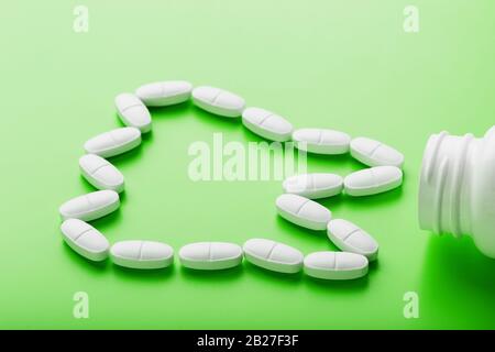 Calcium vitamin in the form of a tooth spilled out of a white jar on a Green background. Pharmacy and dentistry, dental care. Ca, D3, the concept of p Stock Photo