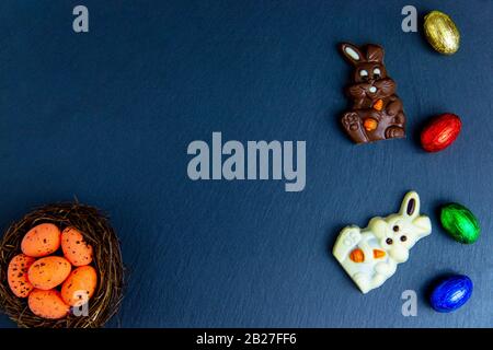 Easter eggs in the nest, chocolate bunny and eggs. Top view on stone table with space for your greetings Stock Photo