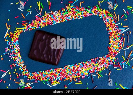 Easter greeting card with colorful candy frame and Easter egg, chocolate bunny and eggs. Top view on stone table with space for your greetings Stock Photo