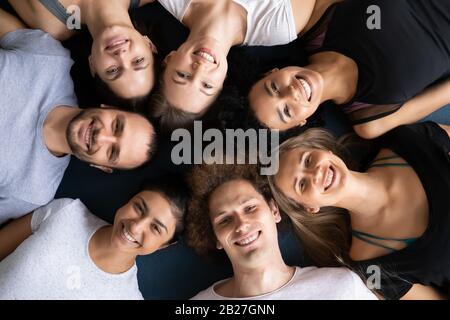 Above view sporty people lying in circle looking at camera Stock Photo