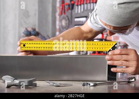 man work in home workshop garage measure metal with ruler angle square, on the workbench with wrenches and hammer, diy and craft concept Stock Photo