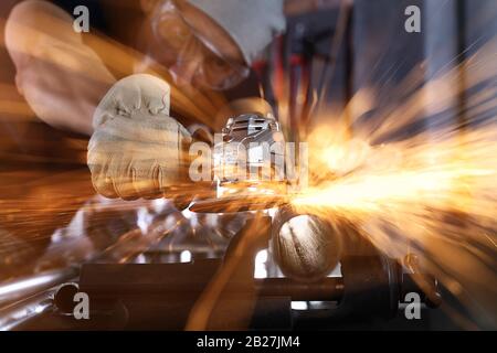man work in home workshop garage with angle grinder, goggles and construction gloves, sanding metal makes sparks closeup, diy and craft concept Stock Photo