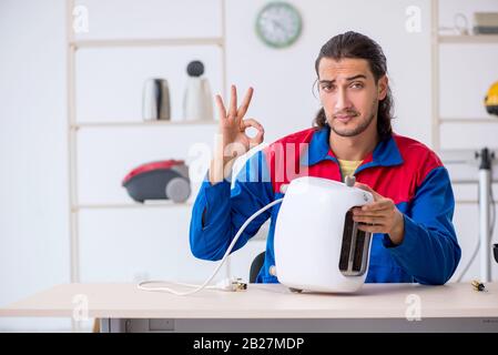 The young male contractor repairing toaster at workshop Stock Photo