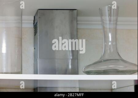 Empty decanter and a glass vase on the kitchen shelf, indoor closeup Stock Photo