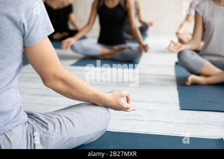 Yogi coach and group of people meditating during yoga class Stock Photo