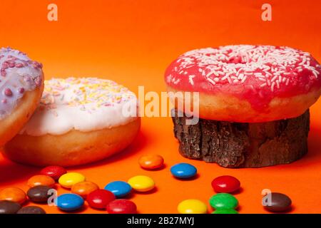 bright multi-colored sweets on an orange background. assorted donuts with candy. Stock Photo