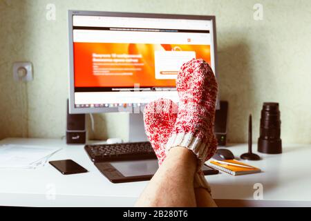 Self-employed work at home on a computer monitor. Study and work online, freelance, warm socks, winter, home comfort and relax Stock Photo