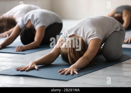 Group of people performing Child Pose focus on caucasian girl Stock Photo