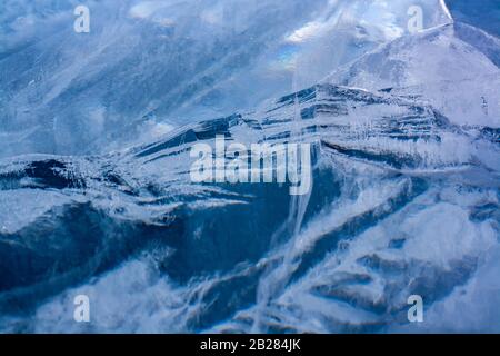 Ice with cracks similar to a mountain landscape. Beautiful ice of blue color. Horizontal. Stock Photo