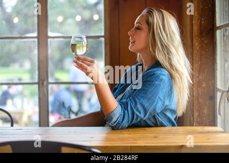 A woman enjoying a delicious craft beer pint in a tulip glass at a bar, pub, restaurant, during weekend Stock Photo