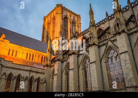 A  illuminated section of York Minster with its medieval gothic architecture and central tower at dawn.  Stained glass windows are lit. Stock Photo