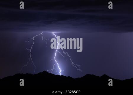 Cloud to ground lightning striking a mountain in the Arizona desert during a monsoon storm Stock Photo