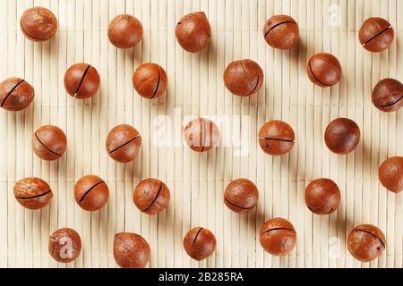 Flat composition with Australian macadamia nuts on bamboo light background. Patterns, repetitions Stock Photo