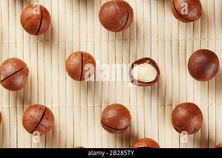 Flat composition with Australian macadamia nuts on bamboo light background. Patterns, repetitions Stock Photo