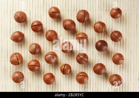 Flat composition with Australian macadamia nuts on bamboo light background. Patterns, repetitions Stock Photo