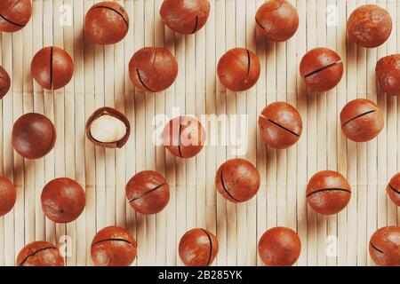 Flat composition with Australian macadamia nuts on bamboo light background. Patterns, repetitions Stock Photo