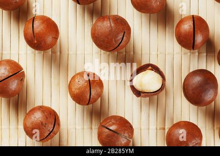 Flat composition with Australian macadamia nuts on bamboo light background. Patterns, repetitions Stock Photo
