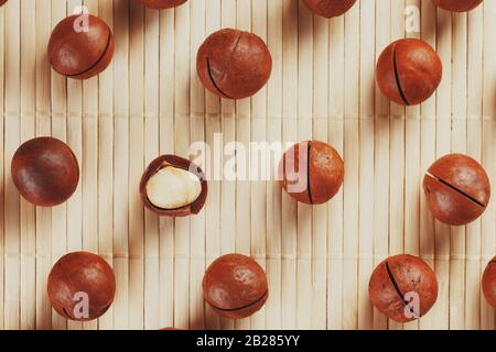 Flat composition with Australian macadamia nuts on bamboo light background. Patterns, repetitions Stock Photo