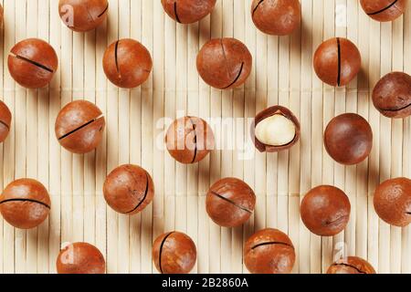Flat composition with Australian macadamia nuts on bamboo light background. Patterns, repetitions Stock Photo