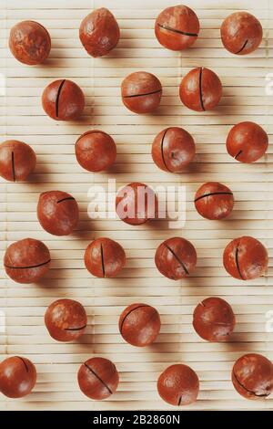 Flat composition with Australian macadamia nuts on bamboo light background. Patterns, repetitions Stock Photo