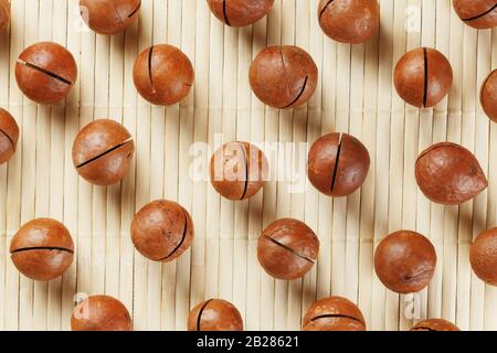 Flat composition with Australian macadamia nuts on bamboo light background. Patterns, repetitions Stock Photo