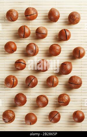 Flat composition with Australian macadamia nuts on bamboo light background. Patterns, repetitions Stock Photo