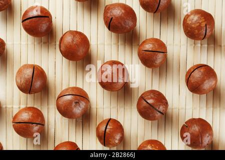 Flat composition with Australian macadamia nuts on bamboo light background. Patterns, repetitions Stock Photo
