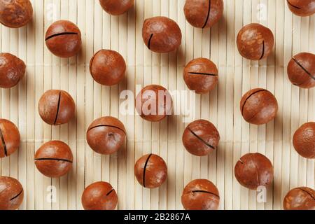 Flat composition with Australian macadamia nuts on bamboo light background. Patterns, repetitions Stock Photo