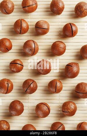Flat composition with Australian macadamia nuts on bamboo light background. Patterns, repetitions Stock Photo