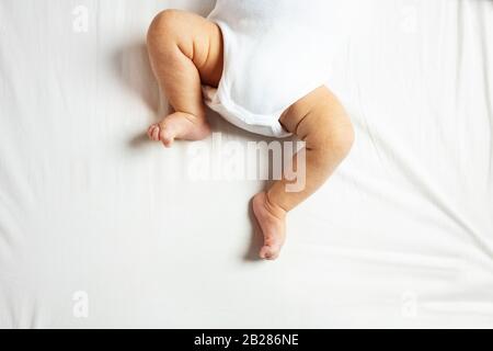 Black baby boy lying on his backside with his legs up in the air