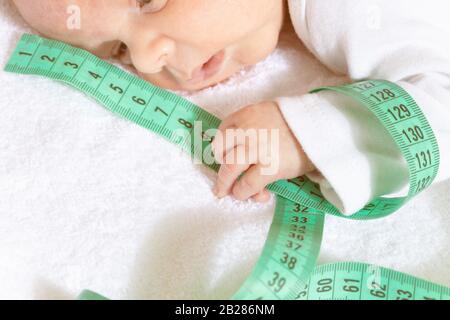 Cute baby infant boy hold with little tiny green centimeter on foreground Stock Photo