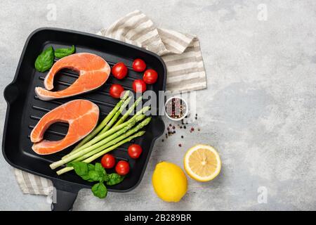 Uncooked salmon steaks and vegetables on metal grill pan. Top view. Ingredients for cooking healthy food rich in omega 3. Copy space for recipe design Stock Photo