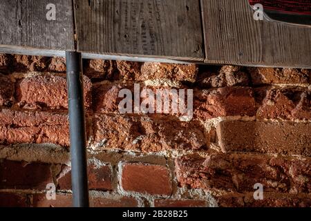 Interior Aged Brick Wall under an aged wood overlay being illuminated natural light from an unseen window. Stock Photo
