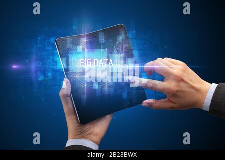 Businessman holding a foldable smartphone with BIG DATA inscription, new technology concept Stock Photo