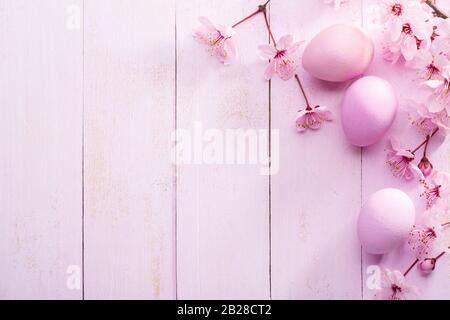 Easter eggs and flowers of  Sakura on an old pink wooden table. Flat lay. Stock Photo