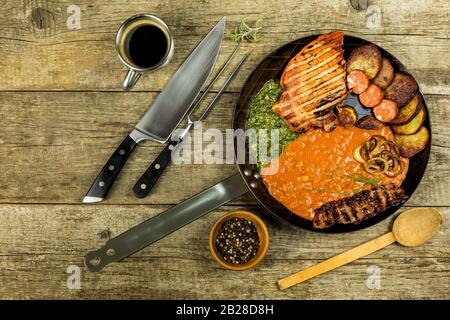 Pork chop on steel pan with beans and spinach. Grilled meat in a frying pan. Caloric food. Fat meal. Fried potatoes with meat in a pan Stock Photo