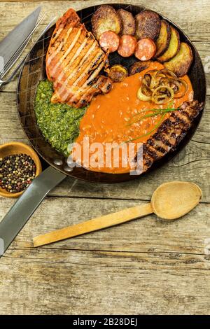 Pork chop on steel pan with beans and spinach. Grilled meat in a frying pan. Caloric food. Fat meal. Fried potatoes with meat in a pan Stock Photo