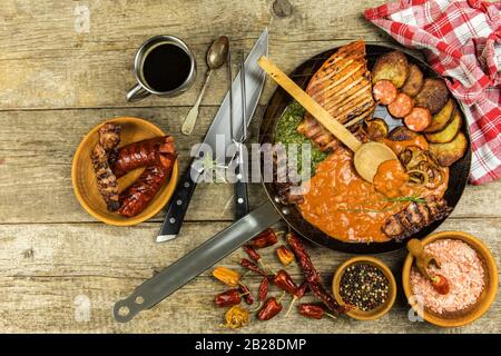 Pork chop on steel pan with beans and spinach. Grilled meat in a frying pan. Caloric food. Fat meal. Fried potatoes with meat in a pan Stock Photo
