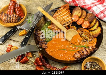 Pork chop on steel pan with beans and spinach. Grilled meat in a frying pan. Caloric food. Fat meal. Fried potatoes with meat in a pan Stock Photo