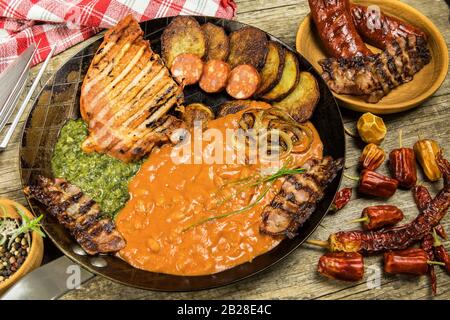 Pork chop on steel pan with beans and spinach. Grilled meat in a frying pan. Caloric food. Fat meal. Fried potatoes with meat in a pan Stock Photo