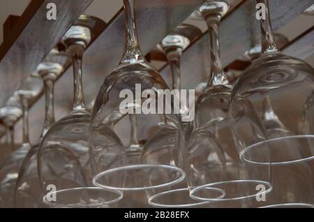 CHEERS:Wine glasses hang from a wooden ceiling rack. Stock Photo